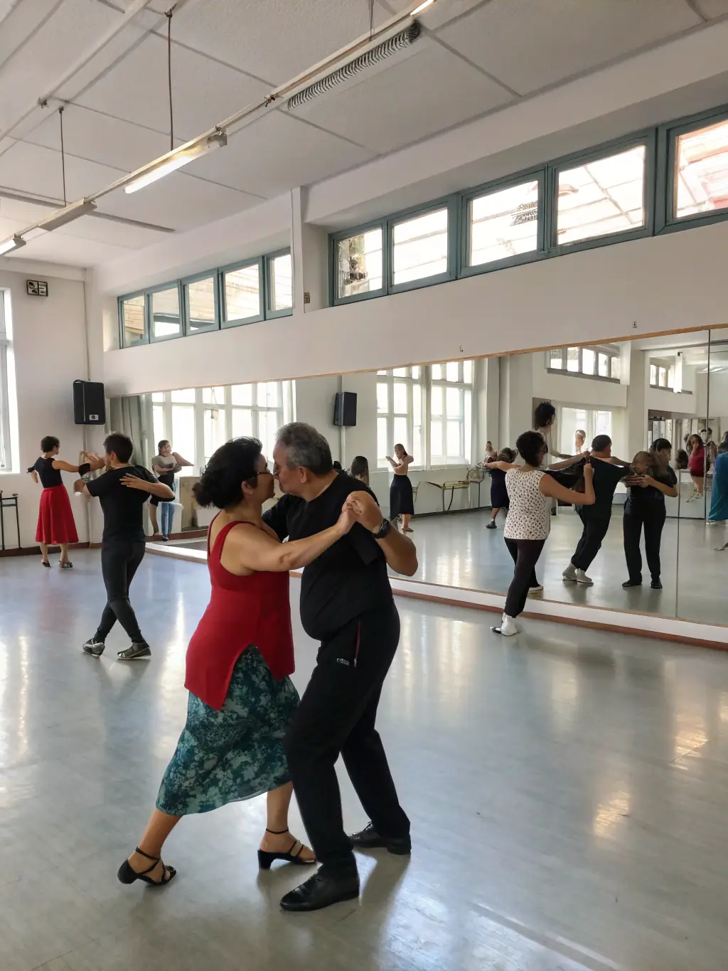 A group of people of different ages learning to waltz in a brightly lit dance studio, with an instructor demonstrating the steps.